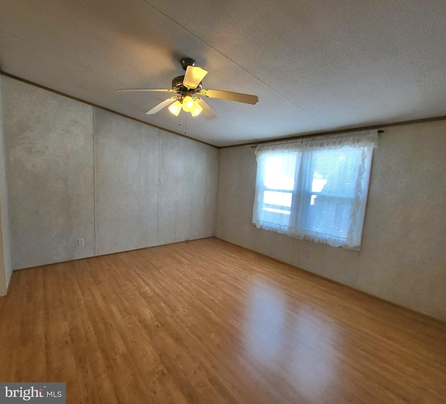 spare room featuring a textured ceiling, ornamental molding, ceiling fan, and light wood-type flooring