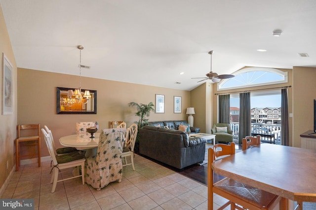 tiled dining area with lofted ceiling and ceiling fan with notable chandelier