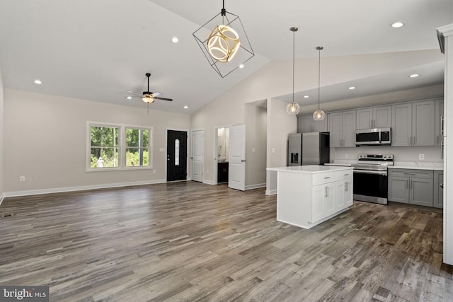 kitchen with gray cabinets, appliances with stainless steel finishes, wood-type flooring, a kitchen island, and decorative light fixtures