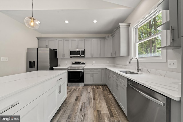 kitchen featuring sink, gray cabinets, stainless steel appliances, wood-type flooring, and decorative light fixtures