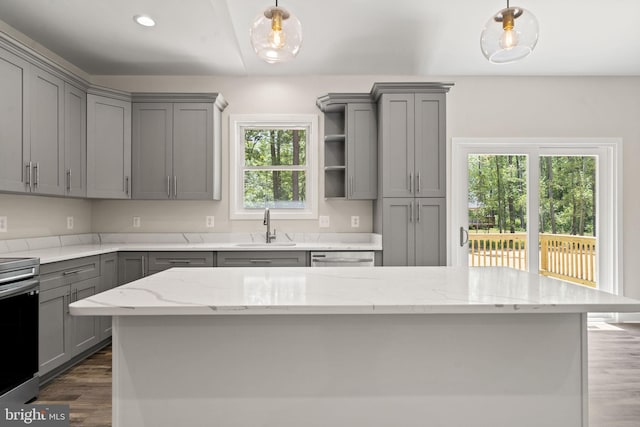 kitchen featuring sink, gray cabinetry, hanging light fixtures, a center island, and light stone counters