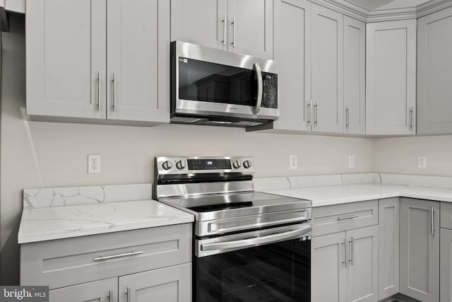 kitchen with gray cabinetry, light stone countertops, and appliances with stainless steel finishes