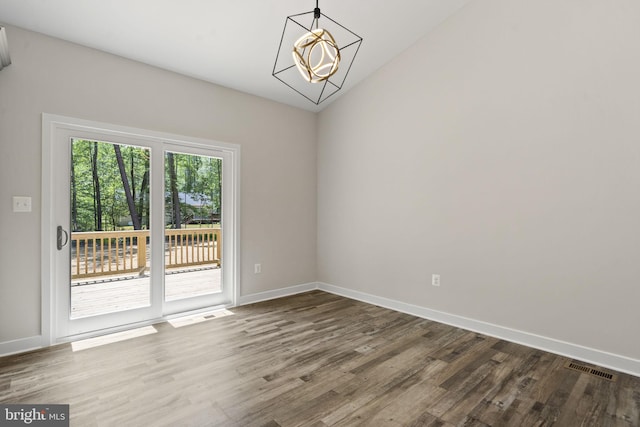 unfurnished room featuring an inviting chandelier, lofted ceiling, and wood-type flooring