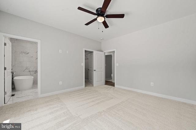 unfurnished bedroom with ceiling fan, ensuite bathroom, a walk in closet, light colored carpet, and a closet