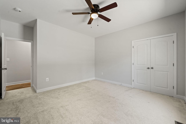 unfurnished bedroom featuring light colored carpet, a closet, and ceiling fan