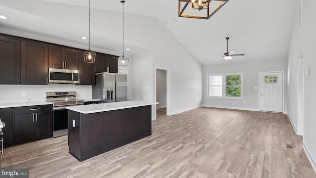 kitchen featuring a kitchen island, pendant lighting, dark brown cabinetry, stainless steel appliances, and light hardwood / wood-style flooring