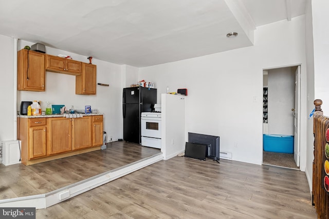 kitchen with light wood-type flooring, white range with gas stovetop, light countertops, and freestanding refrigerator