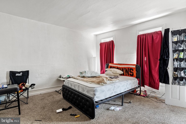 carpeted bedroom featuring a textured wall and baseboards