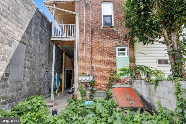 rear view of house featuring brick siding and a balcony