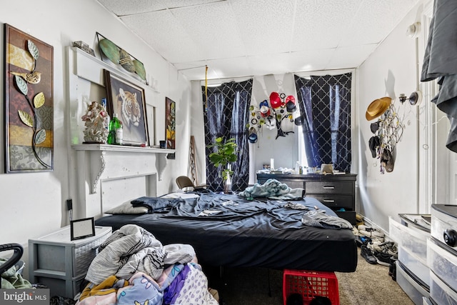 carpeted bedroom featuring a drop ceiling