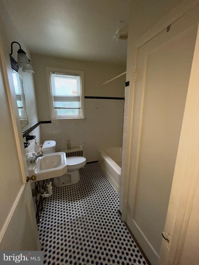 bathroom featuring toilet, tile walls, and sink