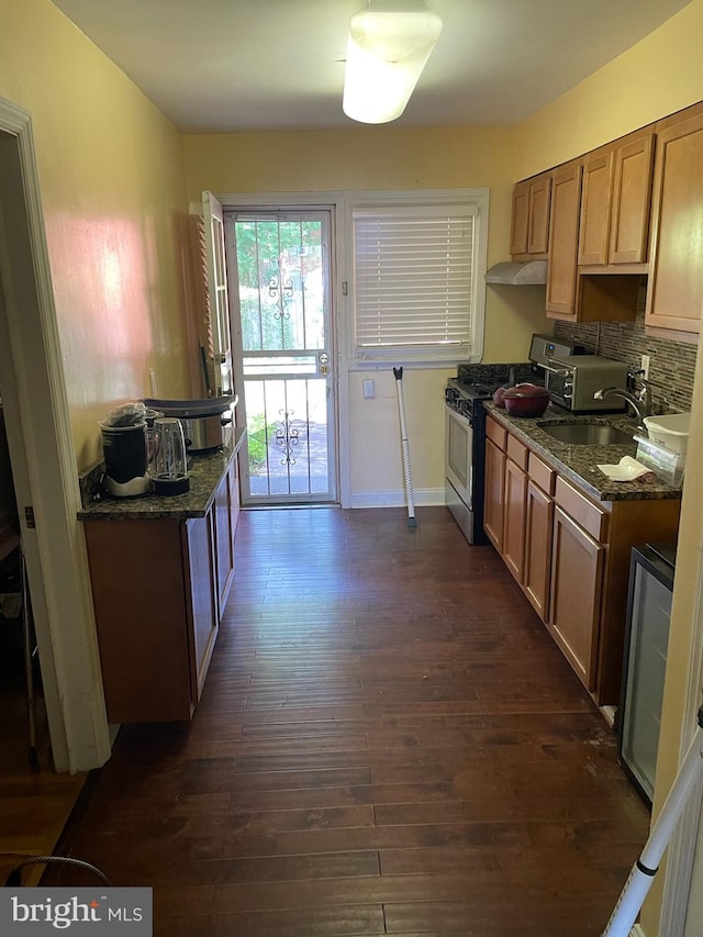 kitchen featuring dark wood-type flooring, dark stone countertops, sink, backsplash, and stainless steel range with gas cooktop