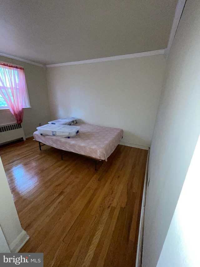 bedroom featuring radiator, ornamental molding, and hardwood / wood-style floors