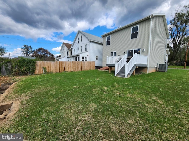 rear view of house with a deck, central AC, and a yard