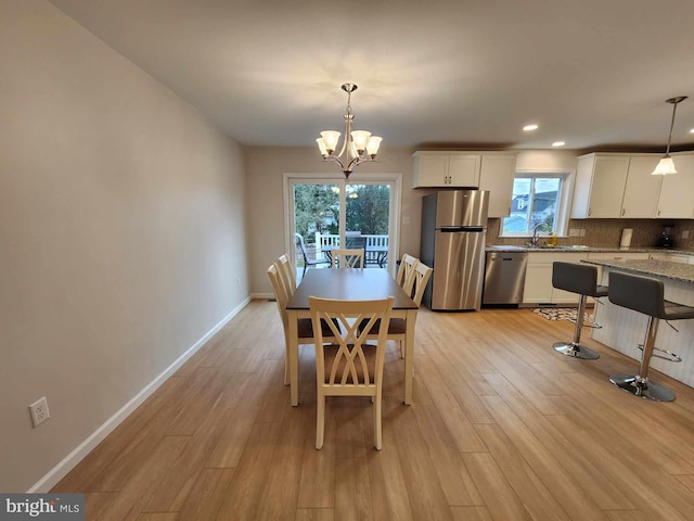 dining space featuring plenty of natural light, an inviting chandelier, and light hardwood / wood-style floors