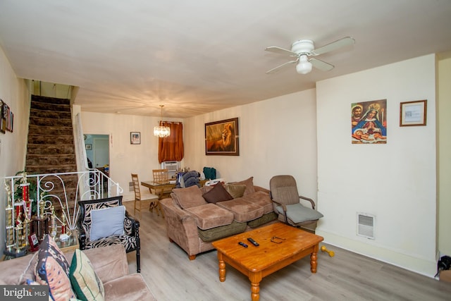 living room featuring ceiling fan with notable chandelier and light hardwood / wood-style flooring