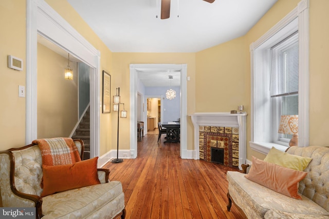 living area featuring ceiling fan, hardwood / wood-style floors, and a fireplace