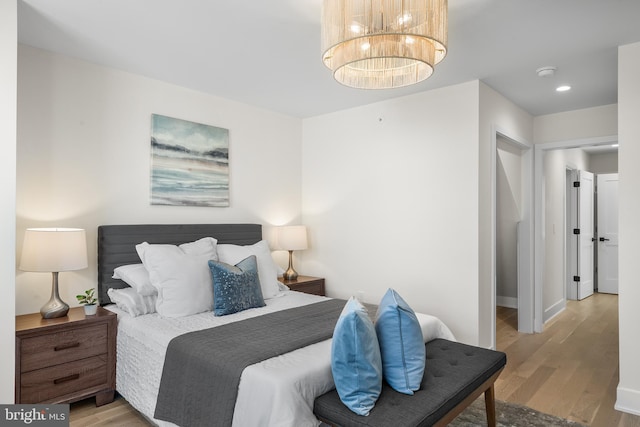 bedroom featuring an inviting chandelier and light hardwood / wood-style floors