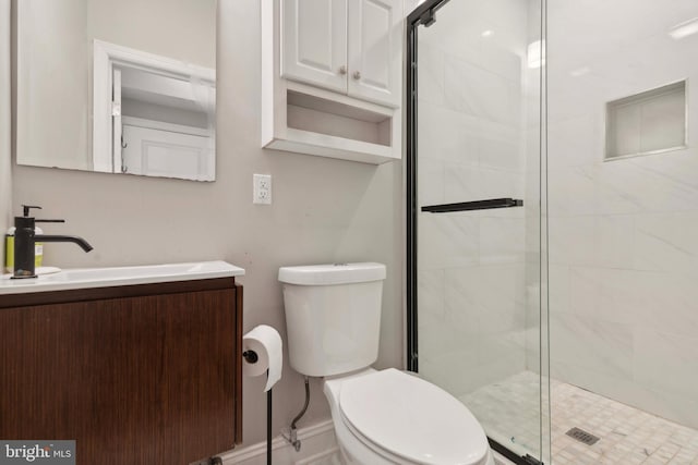 bathroom featuring toilet, vanity, and a shower with shower door