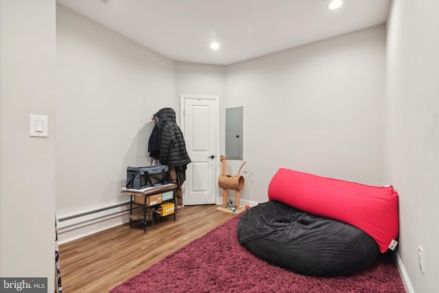 sitting room with a baseboard heating unit, electric panel, and wood-type flooring