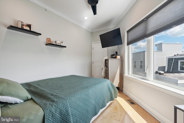 bedroom with ceiling fan, crown molding, and light hardwood / wood-style flooring