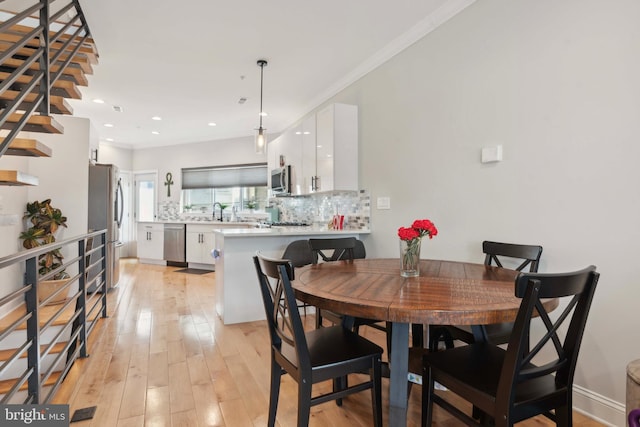 dining area featuring light hardwood / wood-style floors, sink, and crown molding