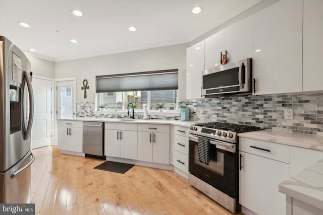 kitchen with tasteful backsplash, light wood-type flooring, stainless steel appliances, and white cabinetry