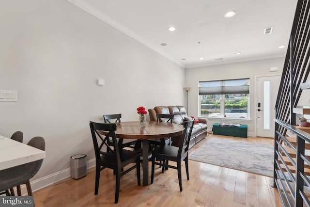 dining area featuring light wood-type flooring and crown molding