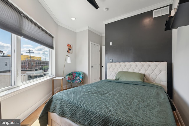 bedroom featuring ceiling fan, crown molding, wood-type flooring, and multiple windows