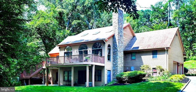 rear view of property with a deck, a garage, and a lawn