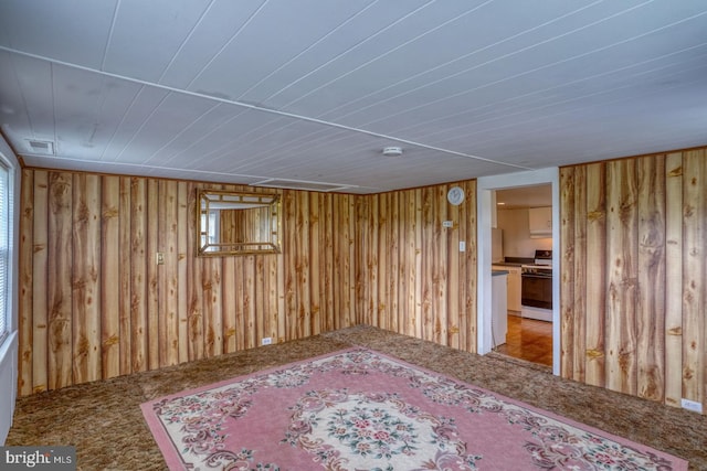 unfurnished room featuring carpet and wood walls