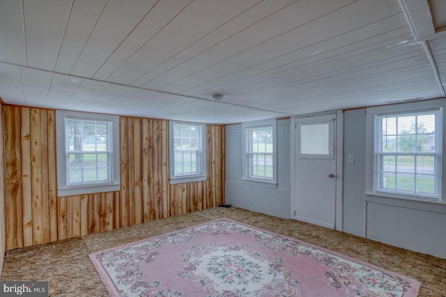 carpeted foyer entrance featuring wood ceiling and wooden walls