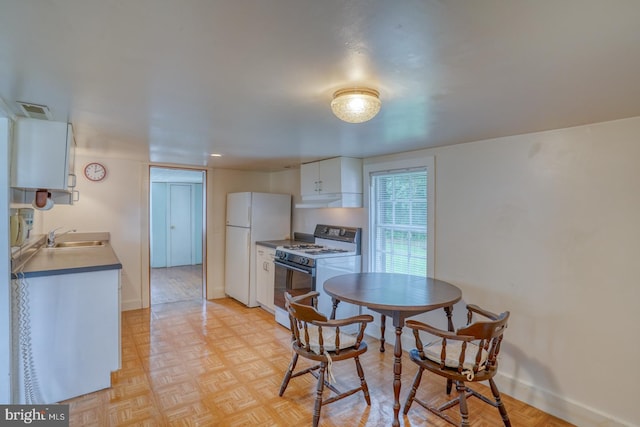 kitchen with white appliances, sink, light parquet floors, and white cabinets