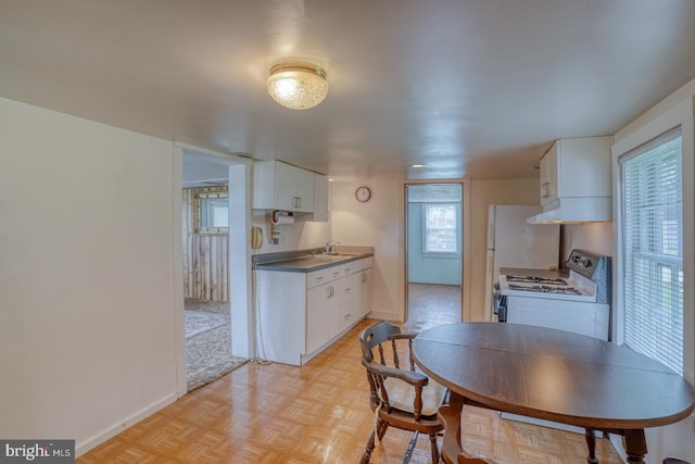 kitchen featuring light parquet flooring, sink, white cabinets, and gas range gas stove