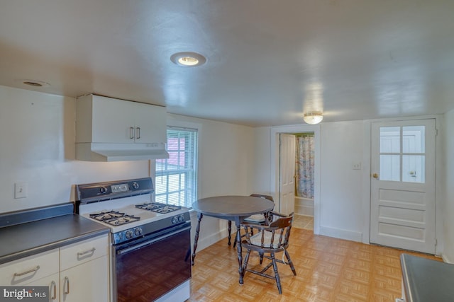 kitchen featuring light parquet flooring, white gas stove, and white cabinets