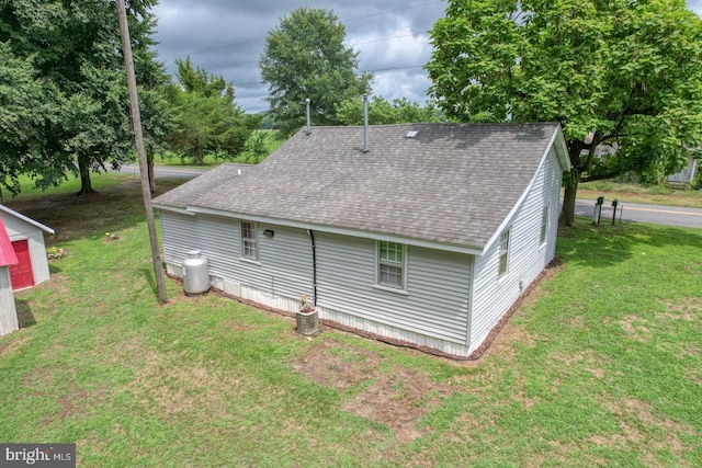 rear view of house with central AC and a lawn