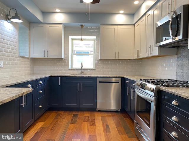 kitchen featuring white cabinetry, appliances with stainless steel finishes, decorative backsplash, light stone countertops, and sink