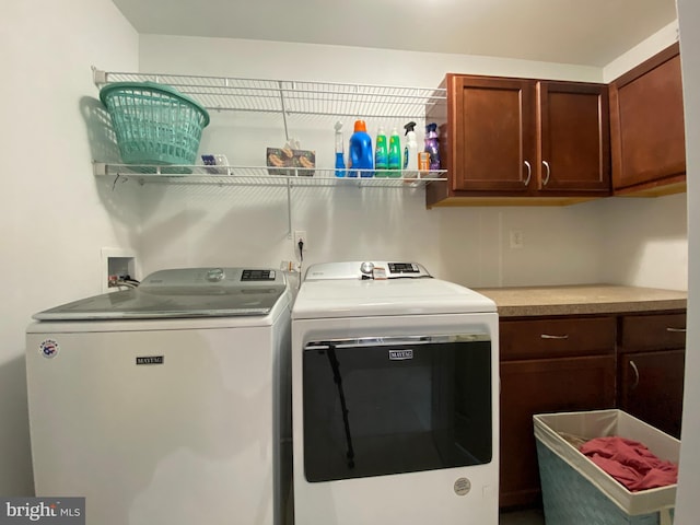 clothes washing area with cabinets and washing machine and clothes dryer