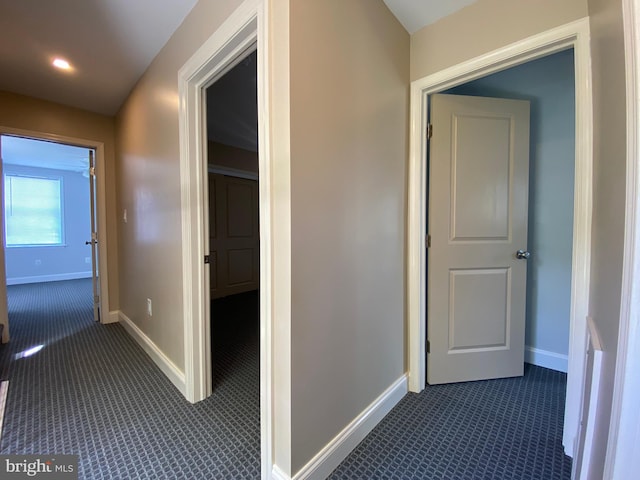 hall with dark colored carpet