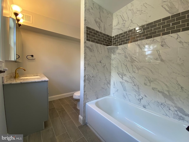 full bathroom featuring toilet, tiled shower / bath, and vanity