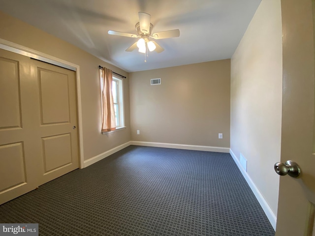 unfurnished bedroom featuring ceiling fan, a closet, and dark colored carpet