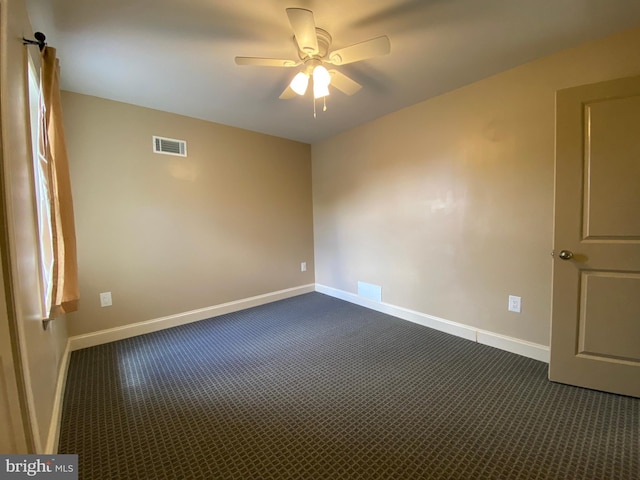 spare room with ceiling fan and dark carpet