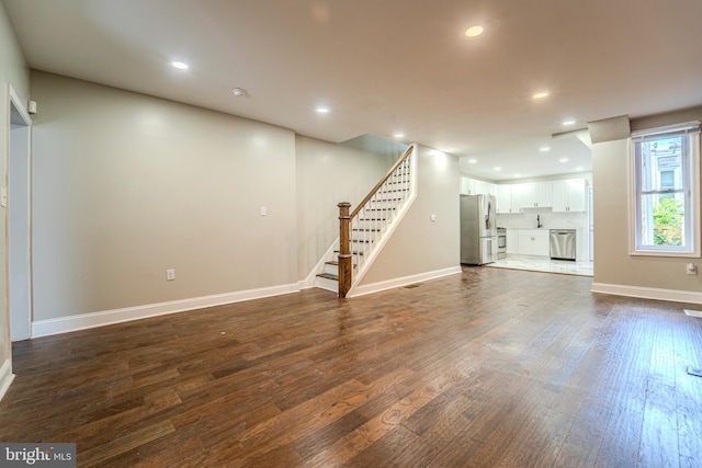 basement featuring hardwood / wood-style flooring and stainless steel refrigerator