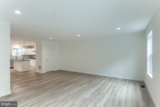 unfurnished living room featuring sink and light hardwood / wood-style flooring