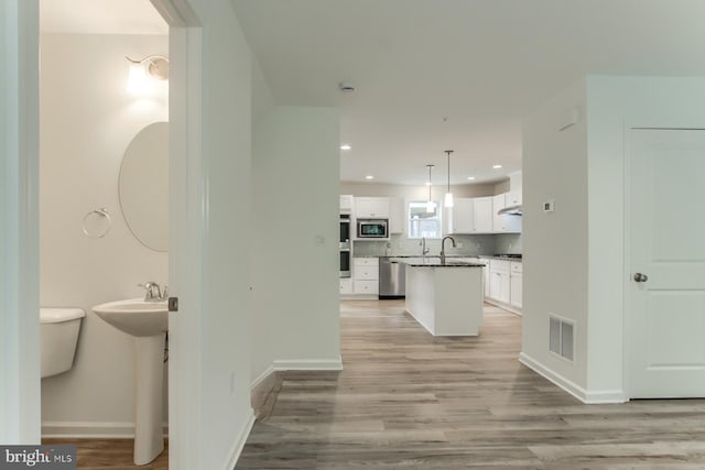 corridor featuring light wood-type flooring and sink