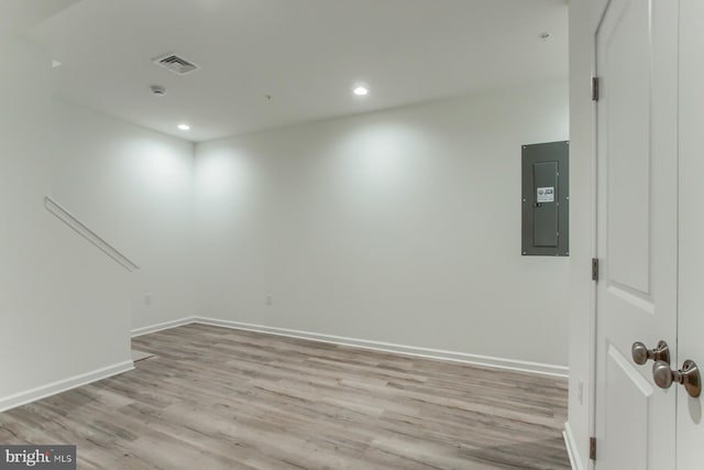 empty room with electric panel and light hardwood / wood-style flooring