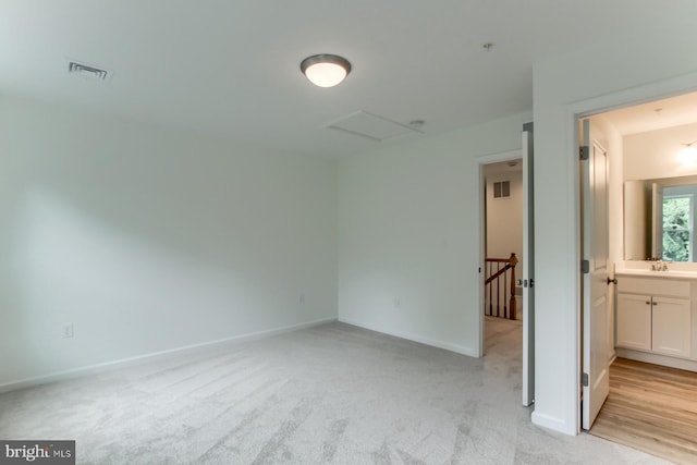 unfurnished bedroom featuring light colored carpet, sink, and connected bathroom