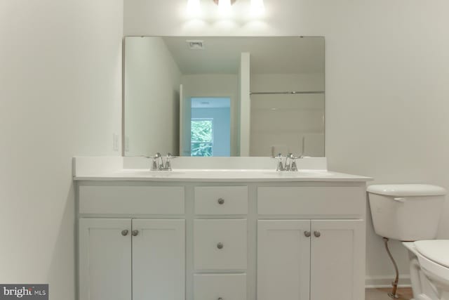 bathroom with toilet, a shower, and vanity