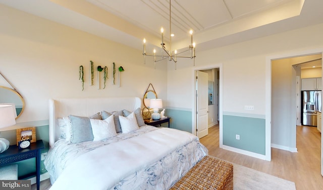 bedroom with stainless steel refrigerator with ice dispenser, an inviting chandelier, and light hardwood / wood-style floors