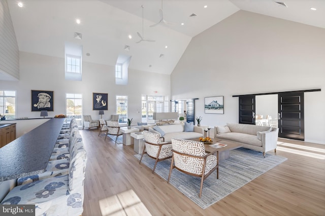 living room featuring light wood-type flooring, ceiling fan, and high vaulted ceiling